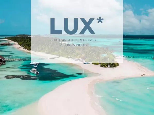 A tropical island with pristine white beaches and turquoise waters. Overwater villas extend into the ocean. Boats are anchored near the shore. The image has a transparent overlay with the text "LUX* South Ari Atoll Maldives Resort & Villas.