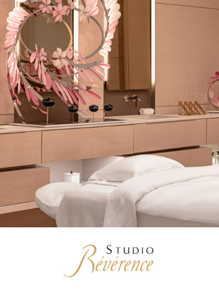 Une salle de spa moderne aux tons clairs avec une table de massage drapée de draps blancs.