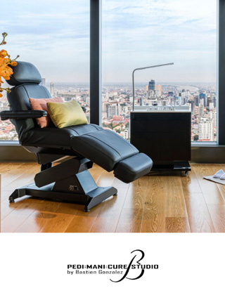 Un luxueux fauteuil de pédicure avec repose-pieds se trouve à côté d’une petite table noire dans un studio moderne doté de baies vitrées.